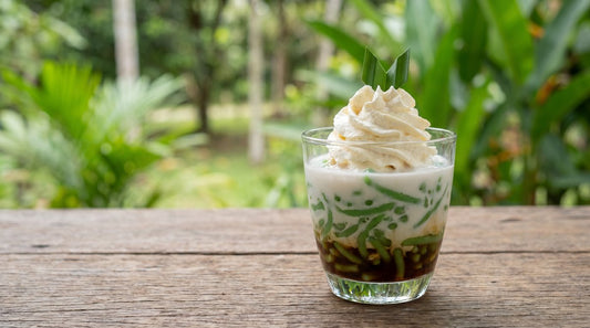 Glass of es cendol dessert with pandan jelly, coconut milk, and whipped pandan coconut foam topping