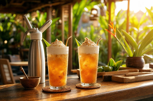 Iced drinks topped with whipped cream foam in a tropical café setting with a cream whipper dispenser