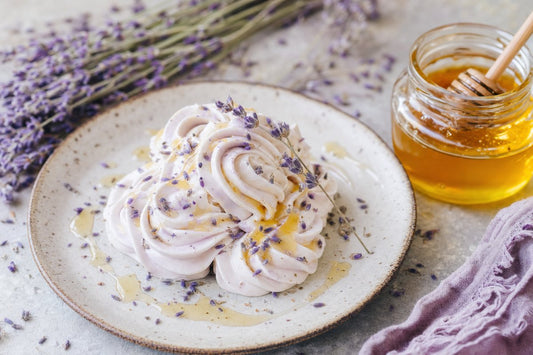 Honey lavender whipped cream rosettes on a ceramic plate with lavender sprigs and honey jar