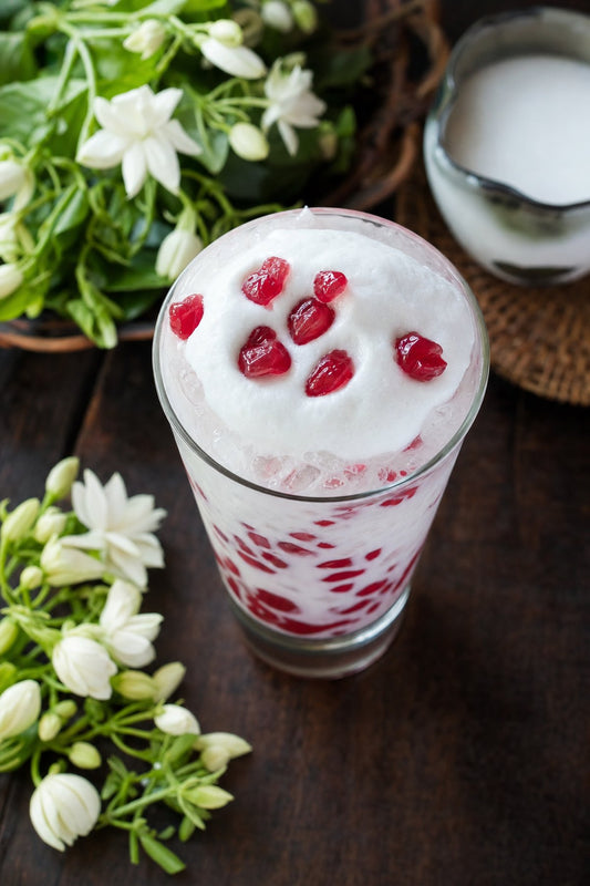 Tab Tim Krob Cream Float – ruby water chestnuts in coconut milk topped with coconut cream foam, served in a tall glass with jasmine flowers